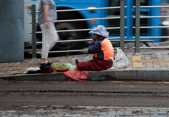24일 오전 밤사이 내린 폭우로 진흙탕이 된 부산역 일대에서 한 할머니가 채소를 팔고 있다. 2020.7.24  연합뉴스