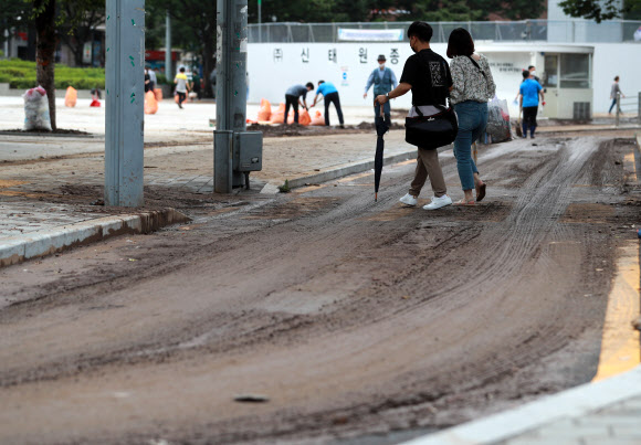 24일 오전 밤사이 내린 폭우로 진흙탕이 된 부산역 일대에서 시민들이 발걸음을 재촉하고 있다. 2020.7.24  연합뉴스