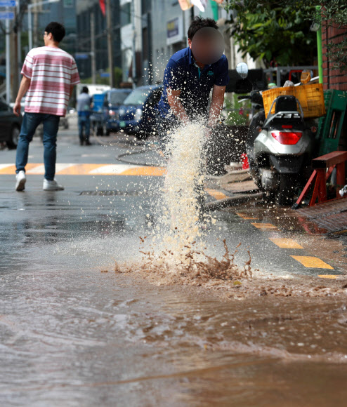 24일 오후 부산 동구 부산역 일대가 밤사이 내린 집중호우로 인해 진흙으로 뒤덮여 있다. 시민들이 배수펌프를 이용해 물을 빼내고 있다. 2020.7.24  연합뉴스