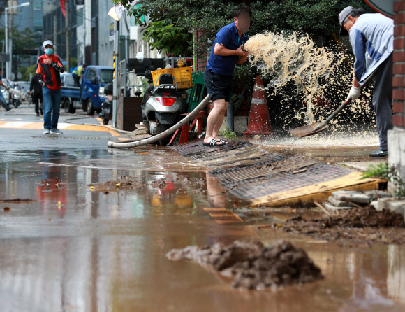 24일 오후 부산 동구 부산역 일대가 밤사이 내린 집중호우로 인해 진흙으로 뒤덮여 있다. 시민들이 배수펌프를 이용해 물을 빼내고 있다. 2020.7.24  연합뉴스