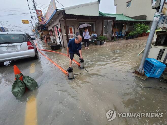 24일 오전 쏟아진 폭우에 침수된 강원 속초시 청호동 저지대에서 주민들이 배수작업을 하고 있다. 연합뉴스 