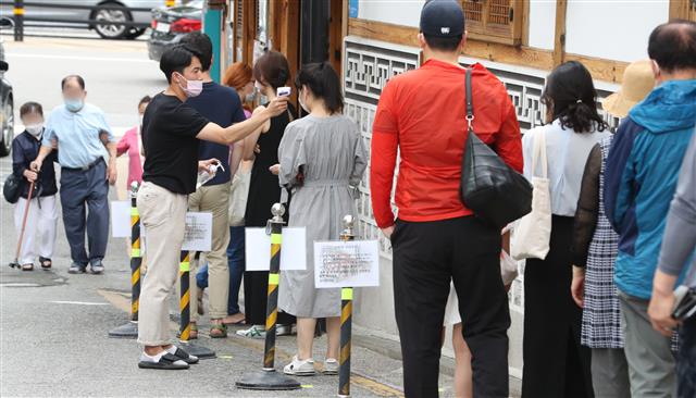 중복인 26일 서울 종로구의 한 삼계탕 전문점을 찾은 시민들이 입장 전 발열 체크를 하고 있다. 2020.7.26 뉴스1
