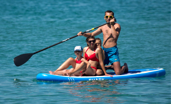 25일(현지시간) 러시아 체르노모르스키 지구  올레네프카의 카라진스카야 베이에서 사람들이 보트를 타고 노를 저으며 여유를 만끽하고 있다. 타스 연합뉴스