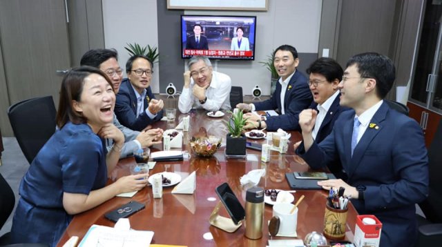 이재정·김승원·박주민·최강욱·김용민·황운하·김남국 의원이 최강욱 열린민주당 대표 의원실에서 ‘처럼회’ 모임을 갖고 있다. 뒤에는 황운하 더불어민주당 의원의 지역구인 대전에서 폭우로 인해 사상자가 발생했다는 뉴스가 나오고 있다. 사진=최강욱 열린민주당 대표 페이스북　