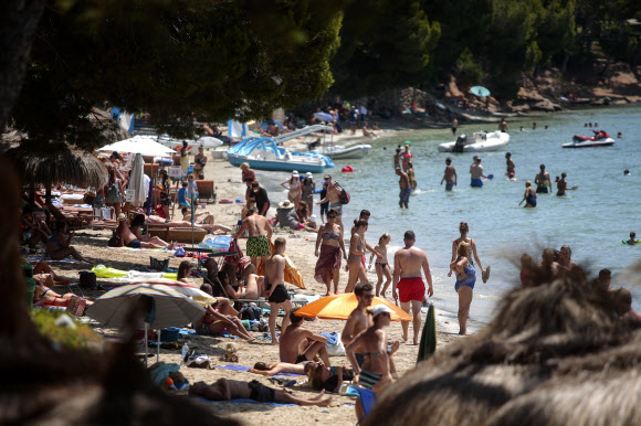 스페인 해변에서 일광욕하는 관광객들