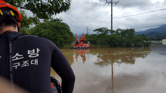 지난 8일 오전 섬진강이 범람하면서 전남 구례군 마산면 도로가 순식간에 물바다가 됐다. 현장 업무를 마치고 복귀하던 소방관들이 시민들을 구조하다가 물이 불어 고립되자 다른 대원들이 출동해 구조하고 있다. 2020.8.9 순천소방서 119산악구조대 제공