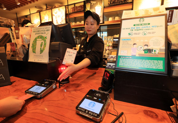 서울시내의 한 스타벅스 매장에서 직원이 고객에게 디지털 결제수단 이용을 안내하고 있다. 스타벅스코리아는 2018년부터 전국의 주요 매장에서 ‘현금 없는 매장’ 운영을 시작했다. 연합뉴스