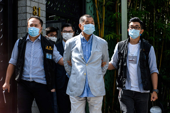 홍콩 민주화 운동가이자 언론 재벌인 지미 라이(가운데)가 10일 홍콩보안법 위반 혐의로 경찰에 체포돼 자택에서 걸어나오고 있다. 홍콩 AFP 연합뉴스