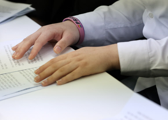 성전환 수술을 받은 뒤 강제 전역 판정을 받은 변희수 전 육군 하사가 11일 오전 서울 종로구 참여연대에서 열린 변 전 하사의 전역 처분 취소를 위한 행정소송 제기 기자회견에서 프라이드 글자가 적힌 기부 팔찌를 손목에 차고 기자회견문을 보고 있다. 2020.8.11  연합뉴스