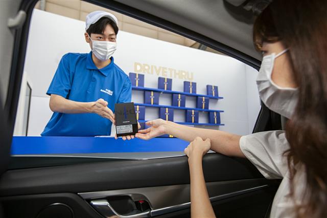 SK텔레콤 홍보모델들이 13일 서울 성동구 복합 쇼핑몰 왕십리 비트플렉스 5층 야외 주차장에서 노트20 드라이브 스루 서비스를 소개하고 있다.  이날 20여명의 일반 고객은 자택에서 SK텔레콤이 마련한 T맵 택시를 타고 현장에 온 다음 본인의 노트20을 안전하게 수령했다. 2020.8.13 뉴스1