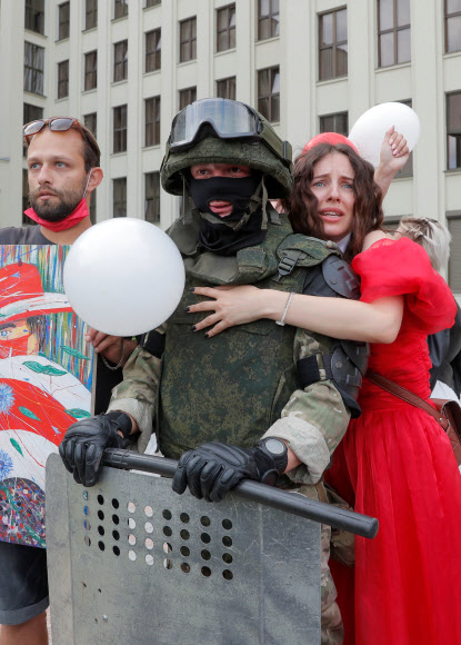 한 참가자가 14일(현지시간) 벨로루시 민스크 독립광장 정부청사 근처에서 경찰의 폭력에 항의하고 대통령 선거 결과를 거부하기 위한 반대 시위 도중 경계를 서고 있는 벨라루시 내무부 부대원을 포옹하고 있다. 로이터 연합뉴스