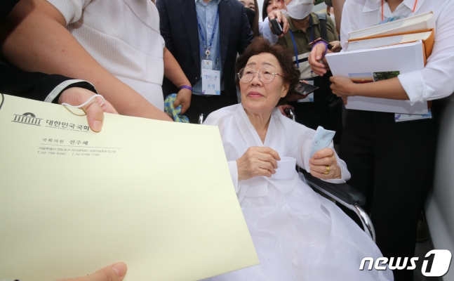 일본군 위안부 피해자인 이용수 할머니가 14일 충남 천안 국립망향의동산에서 열린 일본군 위안부 피해자 기림의 날 기념식에서 기자들과 인터뷰 도중 미래통합당 전주혜 의원이 건넨 서류 봉투를 받고 있다. 천안 뉴스1