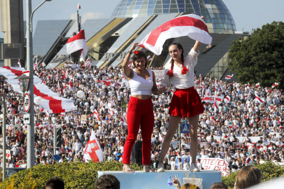 두 여성이 16일(현지시간) 벨라루스 민스크 중심에서 열린 야권 시위 집회에서 오래된 벨라루스 국기를 흔들고 있다. 일주일 동안 시위로 전국을 뒤흔든 야권 지지자들은 수도 벨라루스에서 대규모 행진을 벌이는 것을 목표로 하고 있다. 8월 9일 대통령 선거가 끝나자 시위가 시작됐다. AP 연합뉴스