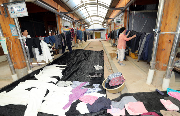 17일 전남 구례군 구례읍 5일장에서 한 상인이 침수 피해를 입은 옷가지를 세탁한 뒤 널어 말리고 있다. 구례 연합뉴스