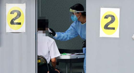 18일 오전 서울 성북구보건소에 마련된 코로나19 임시 선별진료소에서 한 관계자가 코로나19 검사를 받으러 온 주민의 체온을 측정하고 있다. 연합