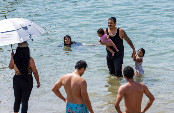 가족들이 18일(현지시간) 미국 캘리포니아 뉴포트 비치의 코로나 델 마르에서 폭염 속에서 더위를 식히고 있다. AP 연합뉴스