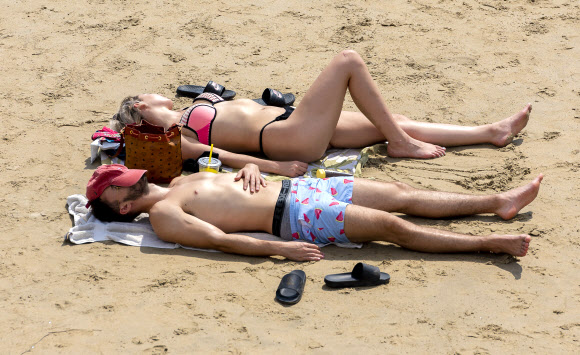 Two people lie in the sun at Corona del Mar in Newport Beach, Calif., Tuesday, Aug. 18, 2020, during hot weather. The National Weather Service issued an excessive heat warning for Southern California. (Leonard Ortiz/The Orange County Register via AP)