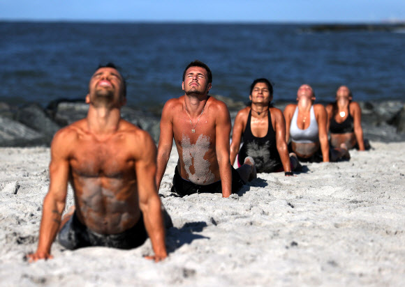 피트니스 클럽 회원들이 18일(현지시간) 미국 뉴욕 롱비치에서 이른바 ‘Life Outside the Box(박스 밖의 삶)’ 운동으로 해변에서 줄을 지어 고난도 자세를 선보이고 있다. 게티/AFP 연합뉴스 