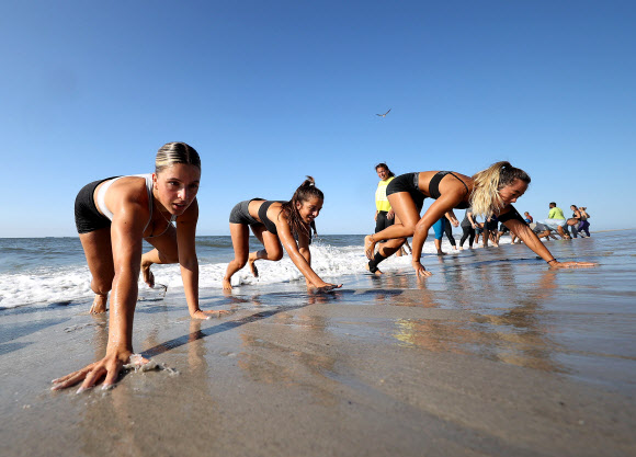 피트니스 클럽 회원들이 18일(현지시간) 미국 뉴욕 롱비치에서 이른바 ‘Life Outside the Box(박스 밖의 삶)’ 운동으로 해변에서 줄을 지어 고난도 자세를 선보이고 있다. 게티/AFP 연합뉴스