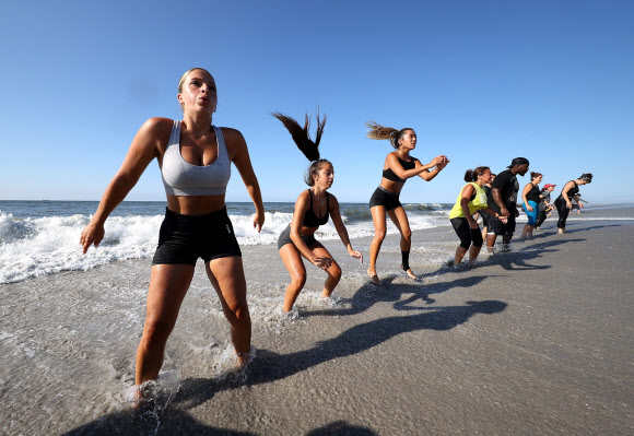 피트니스 클럽 회원들이 18일(현지시간) 미국 뉴욕 롱비치에서 이른바 ‘Life Outside the Box(박스 밖의 삶)’ 운동으로 해변에서 줄을 지어 고난도 자세를 선보이고 있다. 게티/AFP 연합뉴스