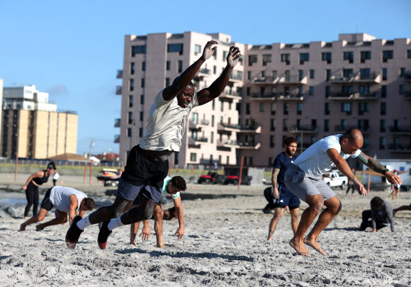 피트니스 클럽 회원들이 18일(현지시간) 미국 뉴욕 롱비치에서 이른바 ‘Life Outside the Box(박스 밖의 삶)’ 운동으로 해변에서 줄을 지어 고난도 자세를 선보이고 있다. 게티/AFP 연합뉴스