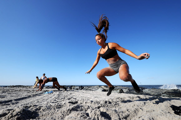 피트니스 클럽 회원들이 18일(현지시간) 미국 뉴욕 롱비치에서 이른바 ‘Life Outside the Box(박스 밖의 삶)’ 운동으로 해변에서 줄을 지어 고난도 자세를 선보이고 있다. 게티/AFP 연합뉴스