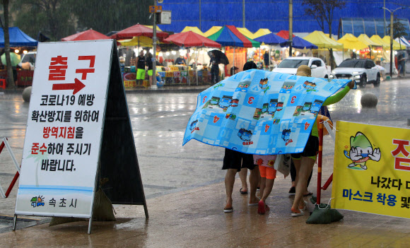 22일 오후 속초지역에 천둥을 동반한 강한 소나기가 쏟아지자 속초해수욕장을 찾았던 피서객들이 돗자리를 우산대용으로 쓰고 이동하고 있다. 2020.8.22  연합뉴스
