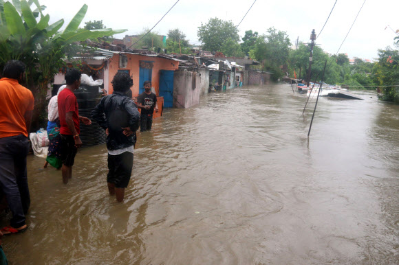 주민들이 22일(현지시간) 인도 보팔에서 폭우가 내려 칼리야소트 강이 위험수위를 넘은 후, 담케다의 침수 지역에서 물 속을 헤치며 다니고 있다. EPA 연합뉴스