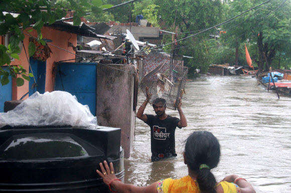 주민들이 22일(현지시간) 인도 보팔에서 폭우가 내려 칼리야소트 강이 위험수위를 넘은 후, 담케다의 침수 지역에서 물 속을 헤치며 다니고 있다. EPA 연합뉴스