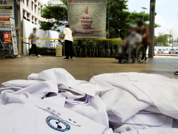 전국의사 2차 총파업 첫날인 26일 오후 경기도 수원시 아주대학교병원에서 의료진이 벗어놓은 가운 앞으로 병원을 방문한 시민들이 지나고 있다. 2020.8.26  연합뉴스