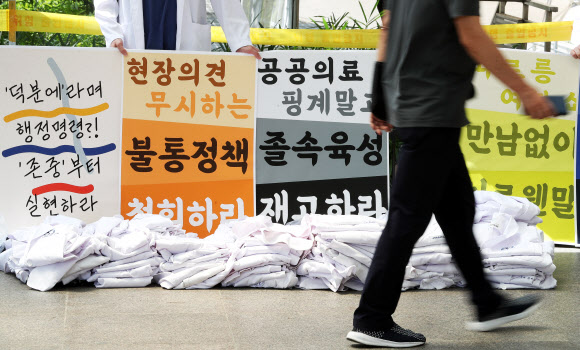 전국의사 2차 총파업 첫날인 26일 오후 경기도 수원시 아주대학교병원에서 의료진이 벗어놓은 가운 뒤에서 피켓 시위를 하고 있다. 2020.8.26  연합뉴스