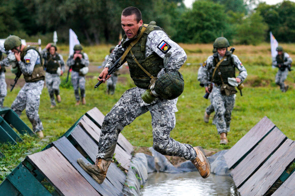 군인들이 26일(현지시간) 러시아 크멜레브카에서 열린 ‘2020 국제군사경연대회’중 해상상륙대회 서비이벌 장애물 코스에 참가해 레이스를 펼치고 있다. 타스 연합뉴스