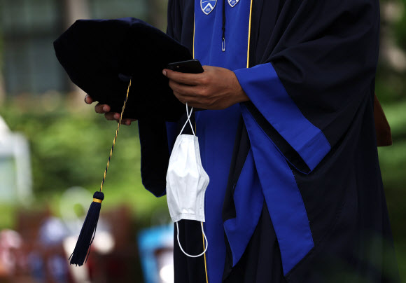 28일 졸업사진 촬영을 위한 가운 대여 행사가 열린 서대문구 연세대학교.  한 졸업생이 학사모와 마스크를 손에 들고 있다. 2020.8.28  연합뉴스