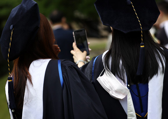 28일 졸업사진 촬영을 위한 가운 대여 행사가 열린 서대문구 연세대학교.  한 졸업생이 목에 건 마스크를 뒤로 넘긴 채 기념사진을 찍고 있다. 2020.8.28  연합뉴스