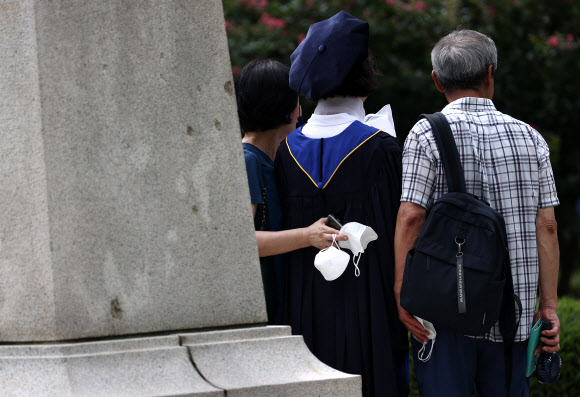 28일 졸업사진 촬영을 위한 가운 대여 행사가 열린 서대문구 연세대학교.  마스크를 벗어 든 졸업생 가족이 카메라 앞에서 포즈를 취하고 있다. 2020.8.28  연합뉴스
