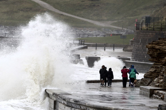 사람들이 29일(현지시간) 영국 노스요크셔주 스카버러에서 바람 부는 해안가를 따라 산책하고 있다. 예보관은 공휴일인 월요일이 영국 일부 지역에서는 기록상 가장 추울 수 있다고 예측하고 있다. 왜냐하면 기온이 연중 평균보다 훨씬 낮을 것으로 예상되기 때문이다. AP 연합뉴스