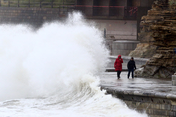 사람들이 29일(현지시간) 영국 노스요크셔주 스카버러에서 바람 부는 해안가를 따라 산책하고 있다. 예보관은 공휴일인 월요일이 영국 일부 지역에서는 기록상 가장 추울 수 있다고 예측하고 있다.  왜냐하면 기온이 연중 평균보다 훨씬 낮을 것으로 예상되기 때문이다. AP 연합뉴스 