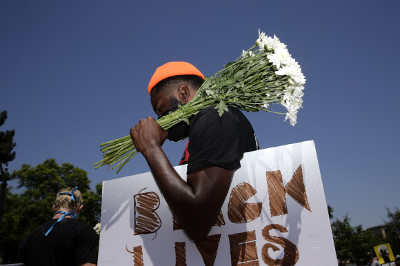지난 7월 20일(현지시간) 미국 로스앤젤레스의 흑인시위에 참석한 한 흑인이 국화꽃을 들고 있다. AP