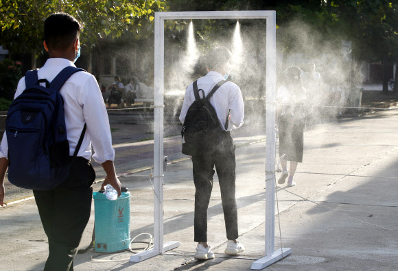 7일(현지시간) 캄보디아 프놈펜의 학교에서 등교하는 학생이 소독약 스프레이 게이트를 통과하고 있다. EPA 연합뉴스