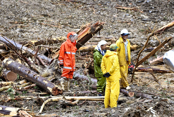 7일 오후 일본 미야자키(宮崎)현 시이바(椎葉)촌에서 남성 3명이 제10호 태풍 하이선이 일으킨 산사태로 건설회사 사무소 겸 주택이 파묻힌 현장에 서 있다. 2020.9.8  교도=연합뉴스
