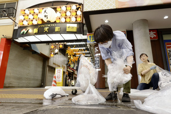 7일 오후 일본 후쿠오카(福岡)시 주오(中央)구의 한 서점 직원이 수낭(침수를 막기 위해 물을 담은 비닐봉지)에서 물을 빼 흘려보내고 있다. 2020.9.8  교도=연합뉴스