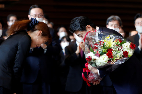 아베 신조 전 일본 총리가 16일(현지시간) 도쿄 총리관저를 떠나며 꽃다발을 받고 고개 숙여 인사하고 있다. 로이터 연합뉴스