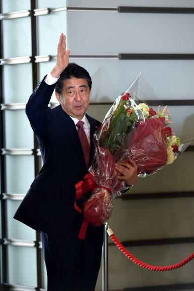 퇴임하는 아베 신조 일본 총리가 16일(현지시간) 마지막 국무회의를 마친 뒤 참모들에게 손을 들어 인사하고 있다. AFP 연합뉴스