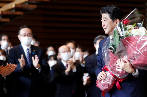 아베 신조 전 일본 총리가 16일(현지시간) 도쿄 총리관저를 떠나며 꽃다발을 받고 있다. 로이터 연합뉴스