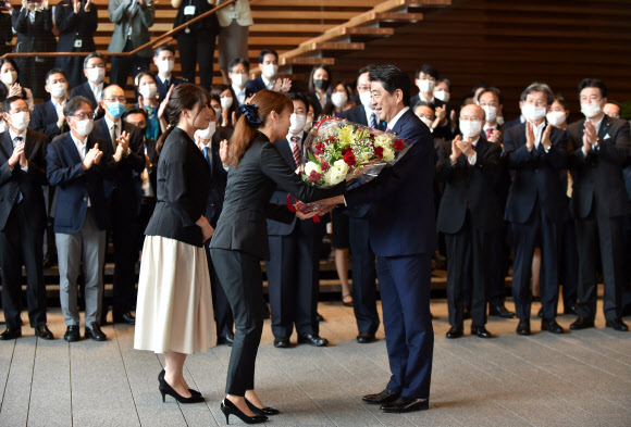 아베 신조 전 일본 총리가 16일(현지시간) 도쿄 총리관저를 떠나며 꽃다발을 받고 있다. AFP 연합뉴스