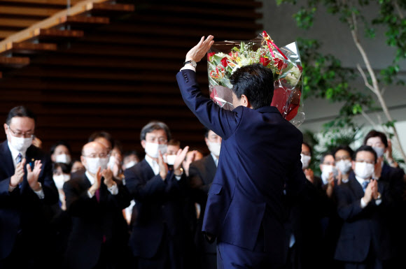 아베 신조 전 일본 총리가 16일(현지시간) 도쿄 총리관저를 떠나며 꽃다발을 받고 손을 들어 인사하고 있다. 로이터 연합뉴스