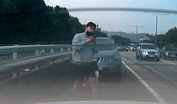 지난 15일 오후 1시쯤 서울 반포동 올림픽대로 갓길에서 고통을 호소하던 여성 운전자를 발견한 정효남씨가 119에 신고전화를 하고 있다. [사진: 독자 제공(김호씨)]