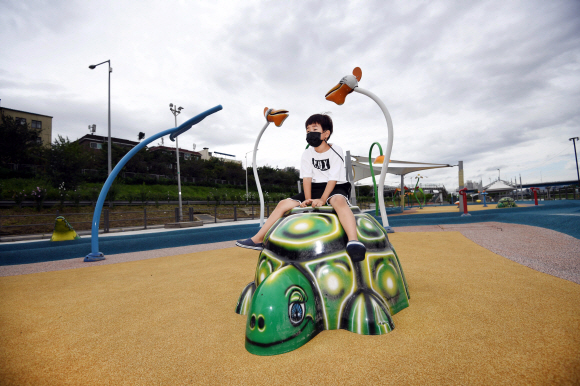 한 어린이가 운영중단된 물놀이장의 거북 모형에 앉아있다.
