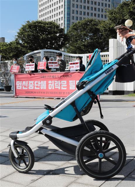 24일 서울 종로구 정부서울청사 앞에서 대학생 페미니즘 연합동아리 ‘모두의 페미니즘’ 회원들이 낙태죄 전면 폐지를 촉구하는 기자회견을 열고 있는 가운데 빈 유모차 한대가 앞을 지나가고 있다. 2020.9.24뉴스1