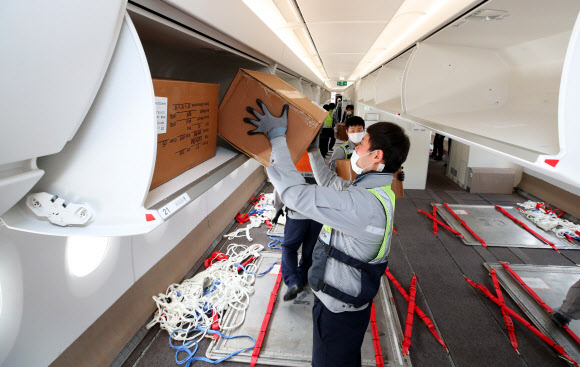 24일 오후 인천국제공항 1터미널에서 아시아나항공 관계자들이 A350 여객기에 화물을 탑재하고 있다. 아시아나항공은 2분기 실적 호조세를 이어가기 위해 A350-900 여객기 1대의 이코노미 좌석 283석을 화물탑재 공간으로 개조했다. 이번 개조로 5톤의 추가 화물을 적재해 편당 23톤의 화물 수송이 가능하다. 2020.9.24  연합뉴스